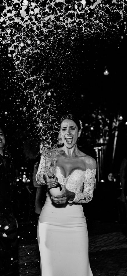 Novia destapando una botella de champán entre risas