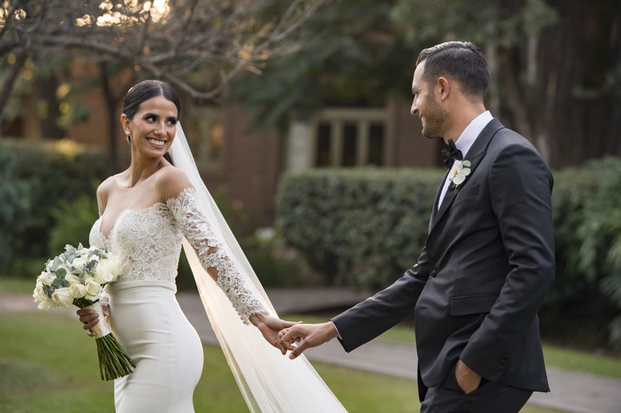 Novios caminando de la mano con el velo al viento