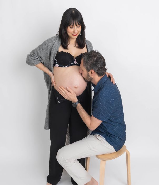 Papá sentado besando el vientre de la futura mamá