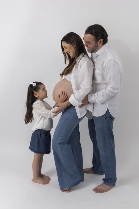 Niña tocando la panza de su mamá junto a su papá